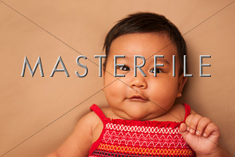 Asian infant wearing red dress on tan background