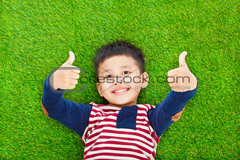 happy kid lying and thumb up  on a meadow