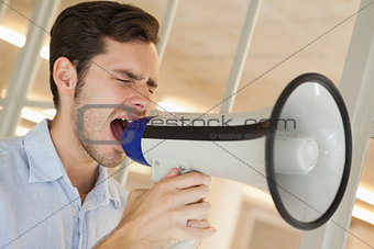 Casual businessman shouting through megaphone