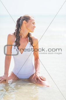 Happy young woman in swimsuit sitting at sea
