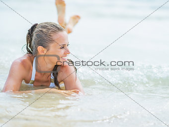 Happy young woman in swimsuit laying on sea coast