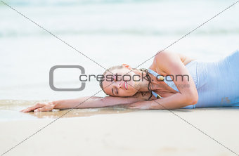 Young woman in swimsuit laying on sea shore