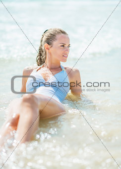Happy young woman in swimsuit laying at seaside