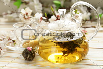 glass teapot with exotic green tea on a wooden table