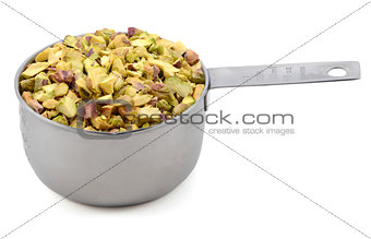 Chopped pistachio nuts in a metal cup measure