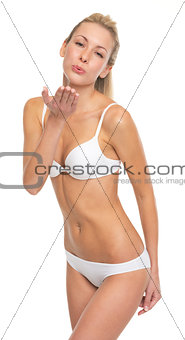 Portrait of happy young woman in lingerie blowing kiss