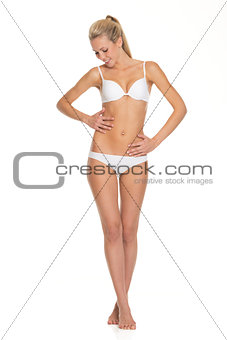 Full length portrait of young woman in lingerie checking body co