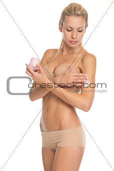 Young woman in lingerie applying creme on hand
