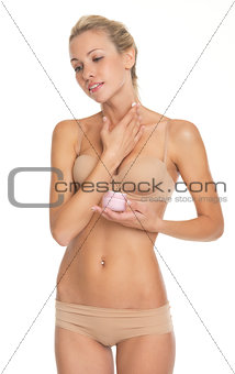 Young woman in lingerie applying creme on neck
