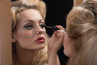 aristocratic girl applying mascara on mirror
