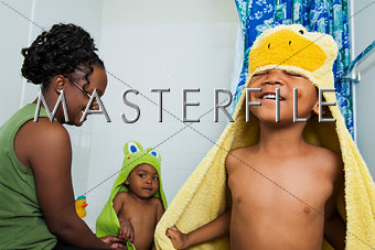 Mom helping boys put on hooded towels after bath