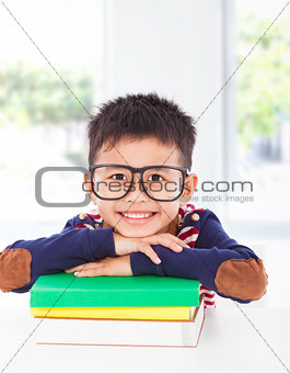 smiling little boy lying on books 