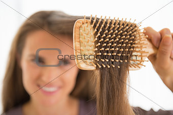 Closeup on happy young woman combing hair