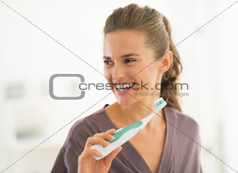 Happy young woman brushing teeth in bathroom