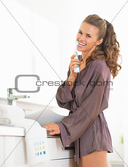 Happy young woman brushing teeth in bathroom