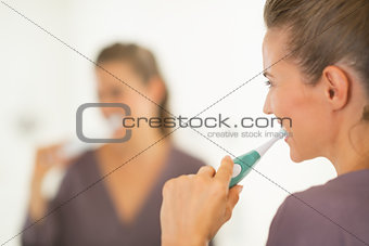 Young woman brushing teeth in bathroom. rear view