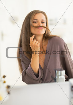 Happy young woman making mustache with hair