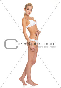 Full length portrait of young woman in lingerie checking body