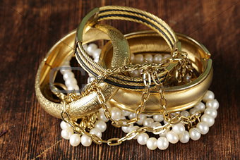 gold and pearl jewelry on vintage wooden background