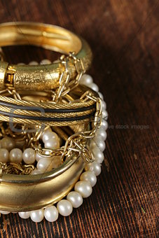 gold and pearl jewelry on vintage wooden background