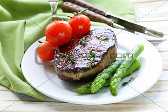 grilled meat beef steak with vegetable garnish (asparagus and tomatoes)