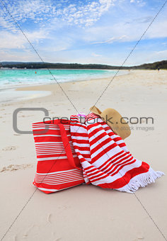 Beach bag towel and hat on the sand