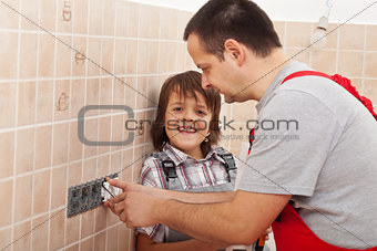 Boy assisting his father installing electical outlets