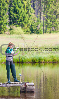 young woman fishing on pier at pond