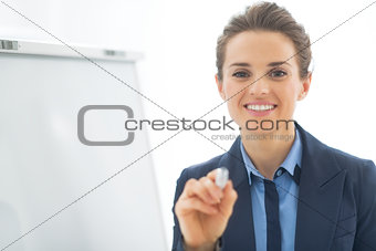 Business woman near flipchart pointing in camera