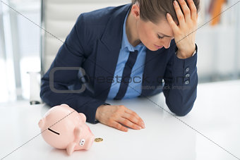Frustrated business woman shaking out coin from piggy bank