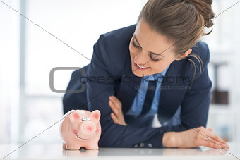 Happy business woman looking on piggy bank