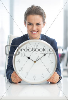 Smiling business woman holding clock