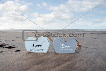 two inscribed wooden love hearts on the beach