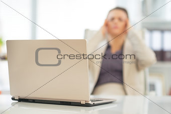 Closeup on laptop on table and stressed business woman in backgr