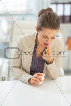 Business woman taking pill at work