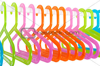 Colored hangers on a rod in a wardrobe