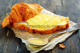 Croissant with cream and teaspoon.