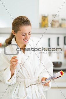 Happy young woman drinking milk in kitchen in the morning