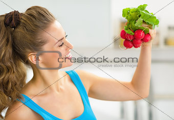 Portrait of happy young woman holding radishes