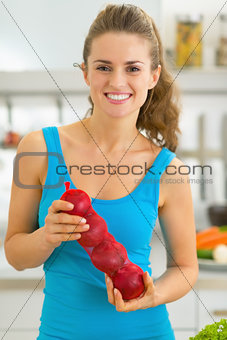 Happy young woman with onion in kitchen