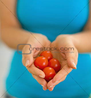 Closeup on young woman showing cherry tomato