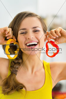 Portrait of happy young woman using bell pepper slices as earrin