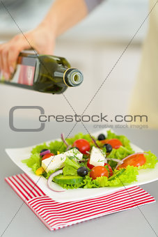 Closeup on young housewife adding olive oil in salad