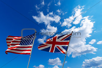 USA and UK flags in the blue sky