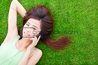 smiling girl lying down on a meadow  and talking by smartphone