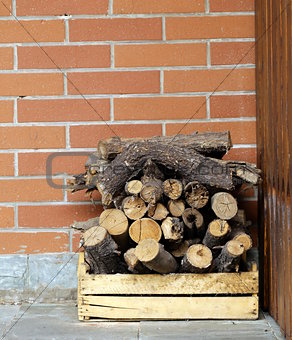 dry chopped firewood logs in a pile on the brick wall background