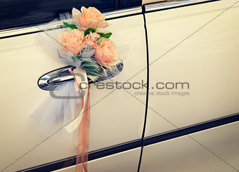 Door of white wedding car with flowers and white bow