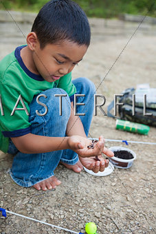 Young boy preparing worm for fishing