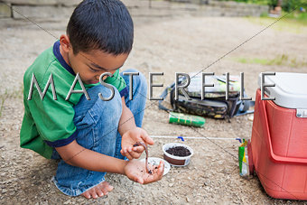 Young boy preparing worm for fishing