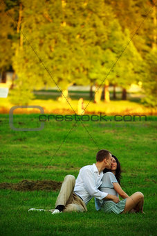 young couple sitting on park lawn